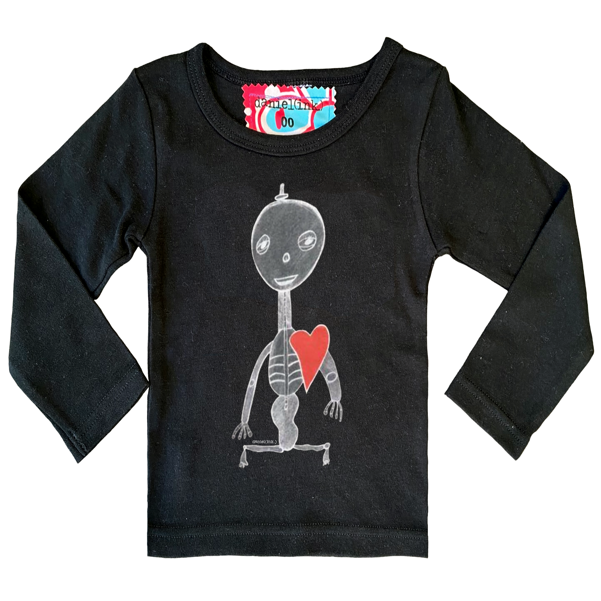Black long sleeve babies’ shirt featuring a hand drawn sketch of a skeleton with a red heart. The shirt has a red, white, and blue fabric label on the back of the neck.