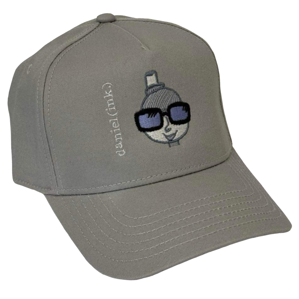 Storm snapback cap featuring an embroidered image of a person's head in silver. The person is wearing a small top hat and big sunglasses with black frames and blue lenses. The name daniel(ink.) is embroidered in silver thread next to the person's head.