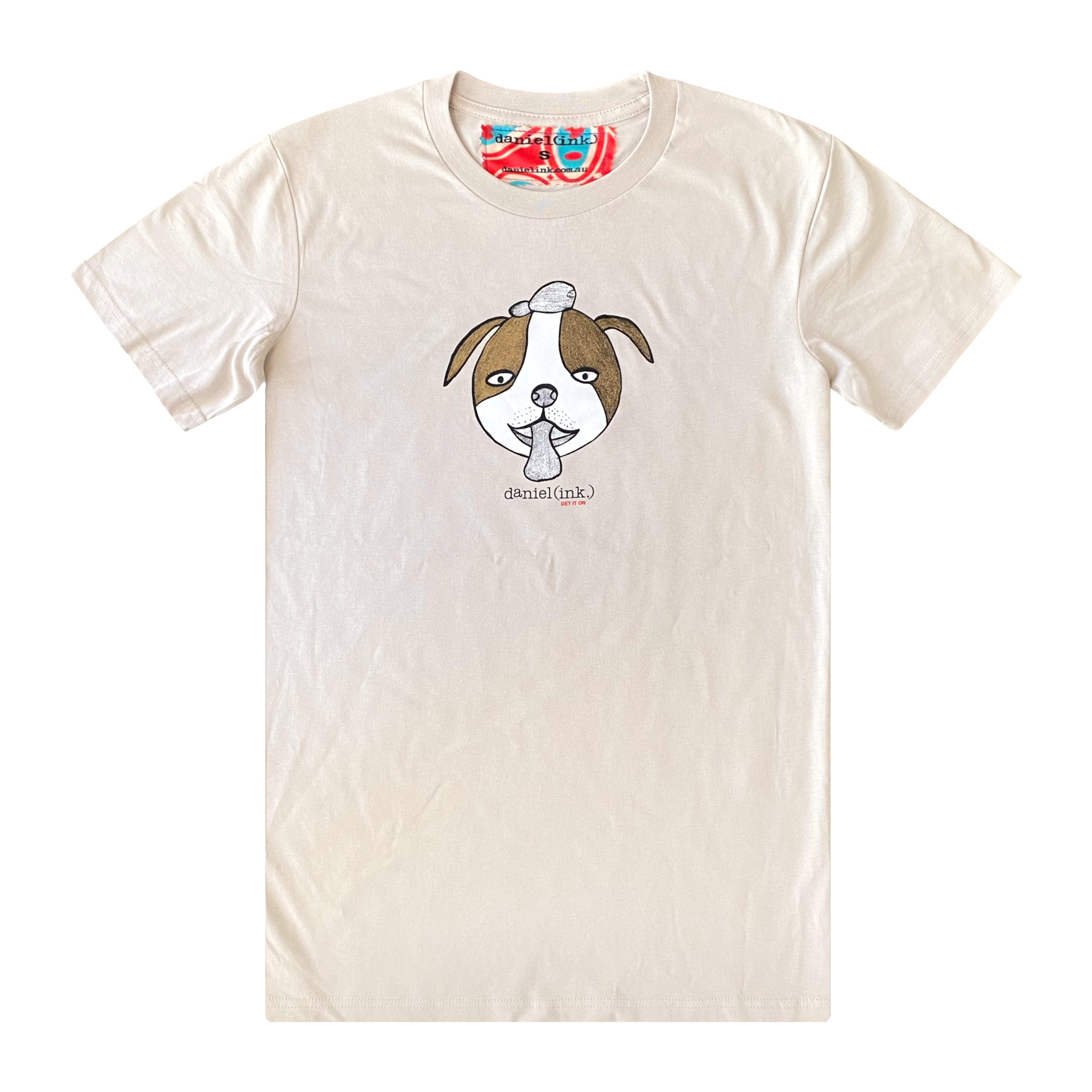 Men's bone colour t-shirt featuring a hand drawn sketch of a dog’s face in brown and white. The dog has a round head, floppy ears, wide eyes, and its tongue is sticking out. The t-shirt has a red, white, and blue fabric label on the back of the neck.