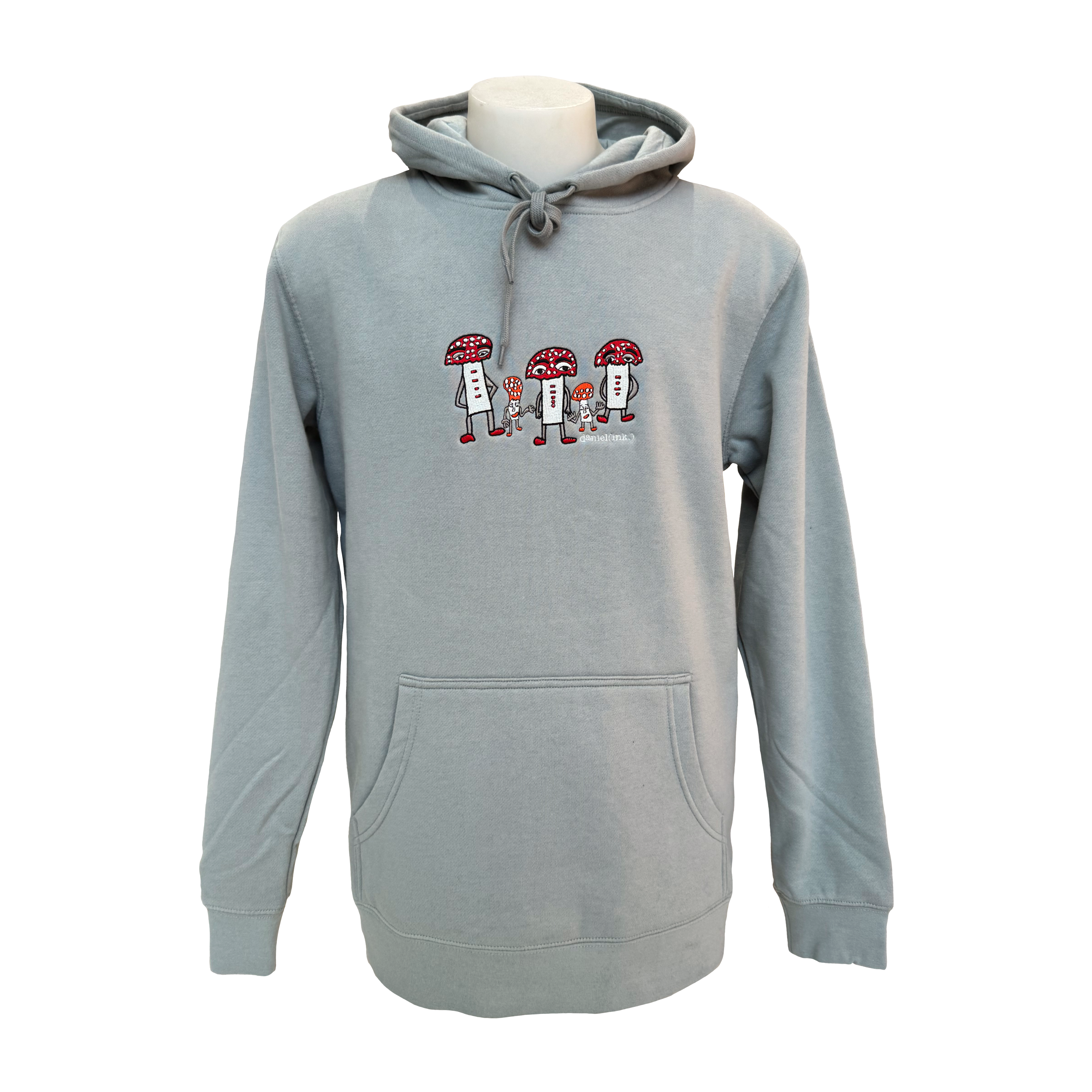 Unisex storm coloured hoodie featuring an embroidered image of five humanoid mushroom figures, three large and two small, standing next to each other. Each mushroom figure has a red mushroom cap, red shoes, and red accents. The three large mushrooms also have red buttons on their chests which spell "magic" in Morse code. The name daniel(ink.) is embroidered in silver thread underneath the mushroom people.